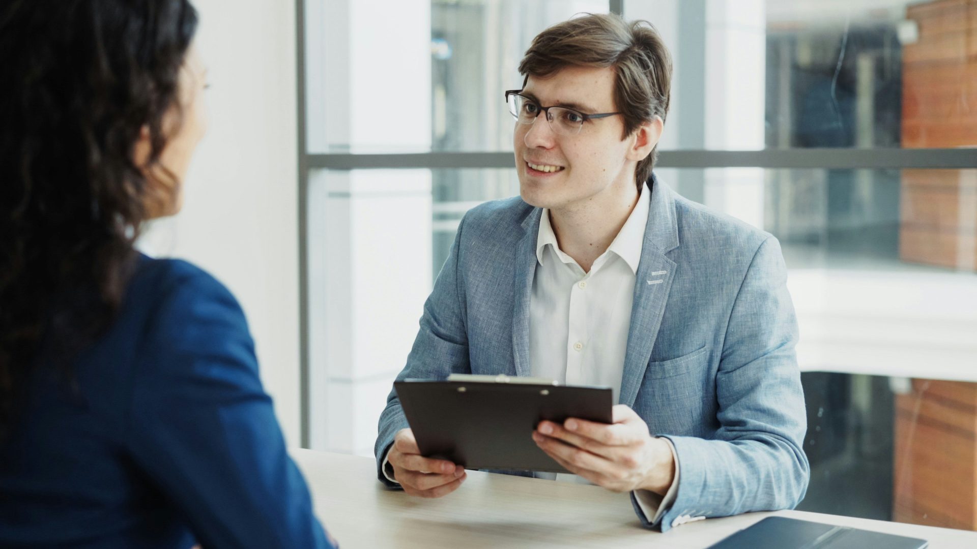 Man in suit interviews woman holding clipboard