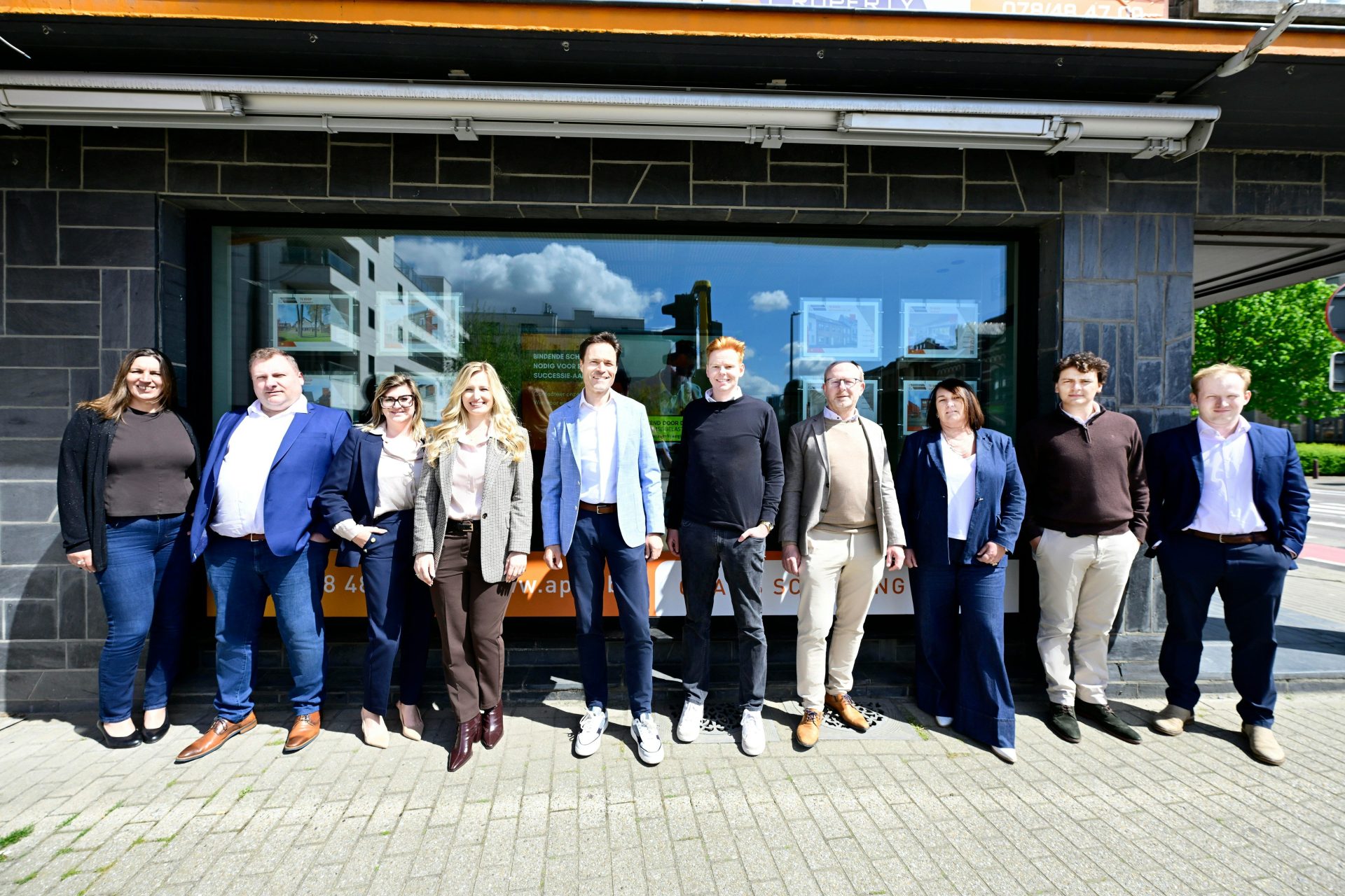 Ten business professionals standing together outside an office building