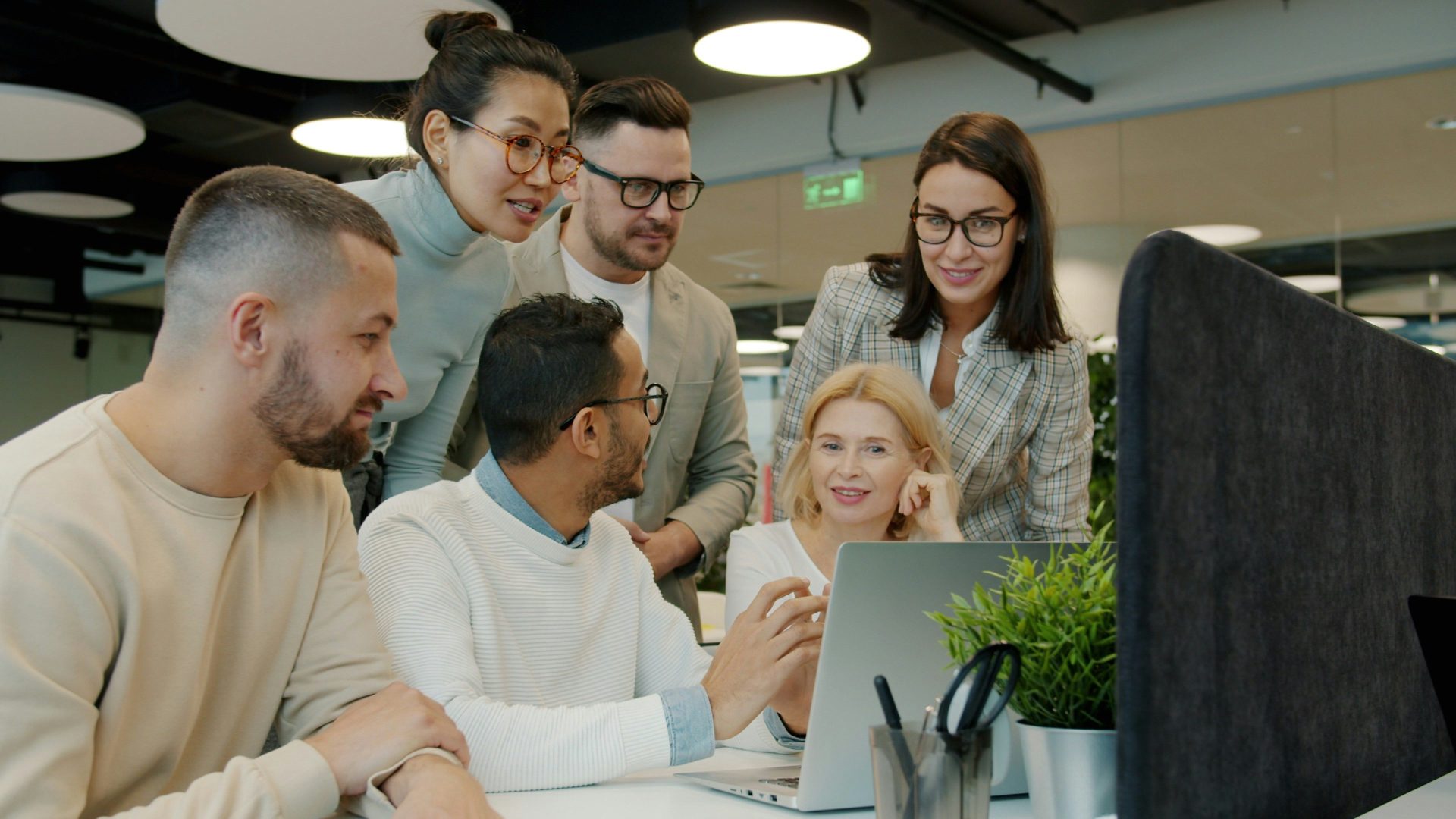 Diverse team collaborating around a laptop in office